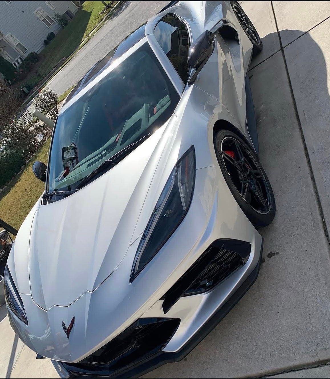 A silver mid-engine Corvette, detailed, on a driveway