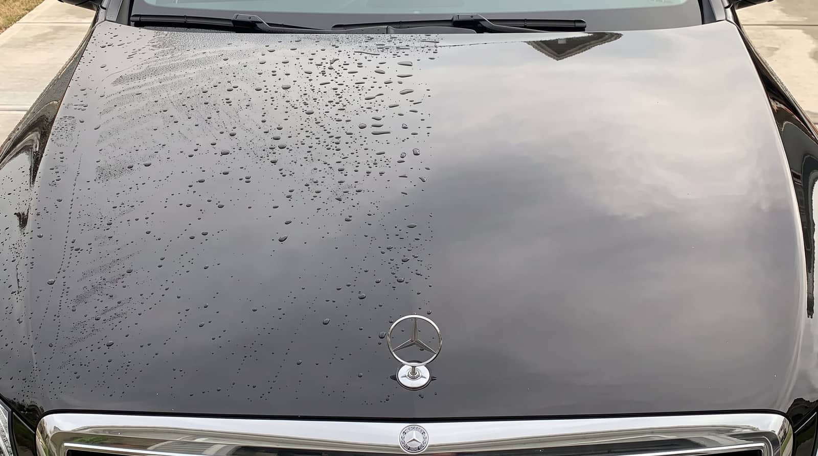 Water beading on the black hood of a Mercedes after a wash