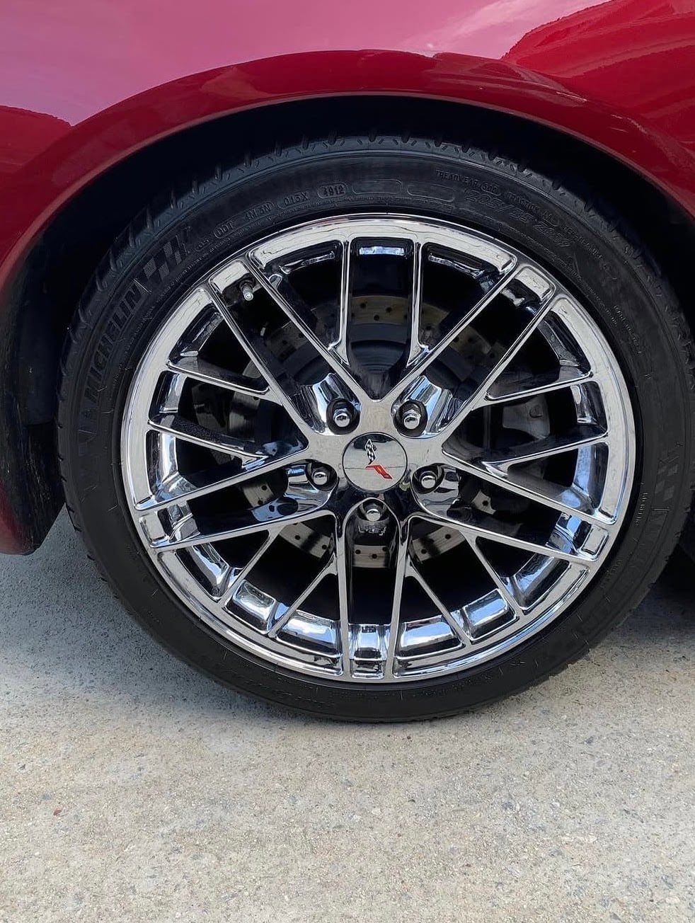A polished chrome Corvette wheel with a dressed tire